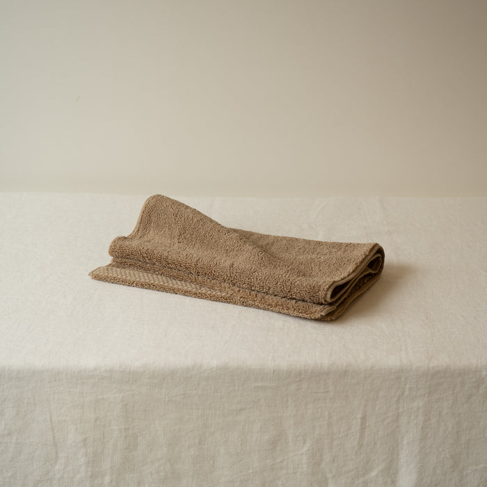 Folded beige towel on a white surface with a neutral background