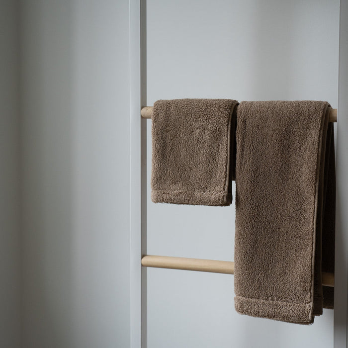 Brown towels hanging on a towel rack against a white wall