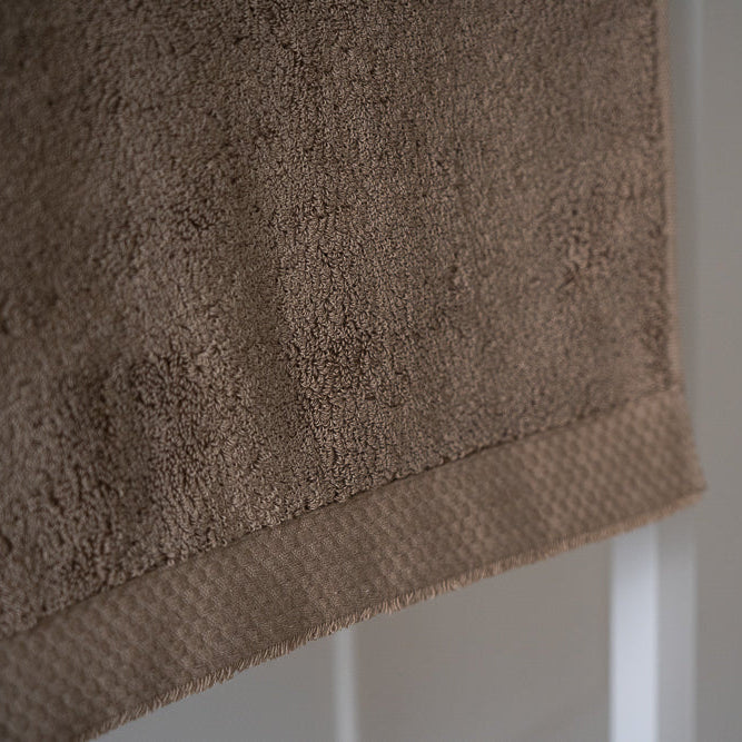 Brown towel hanging against a white wall