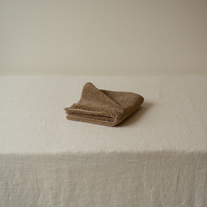 Folded brown towel on a beige surface