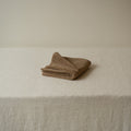Folded brown towel on a beige surface