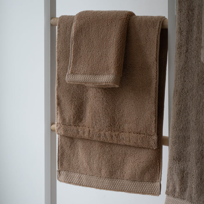 Brown towels hanging on a towel rack against a white background
