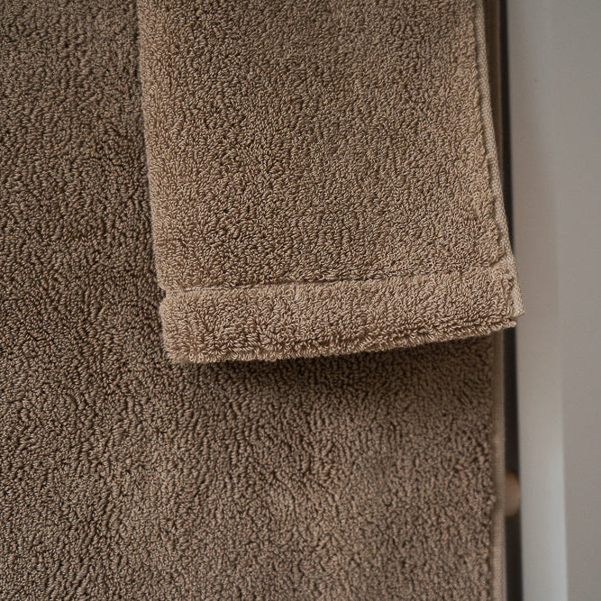 Brown towel on a textured surface with a neutral background