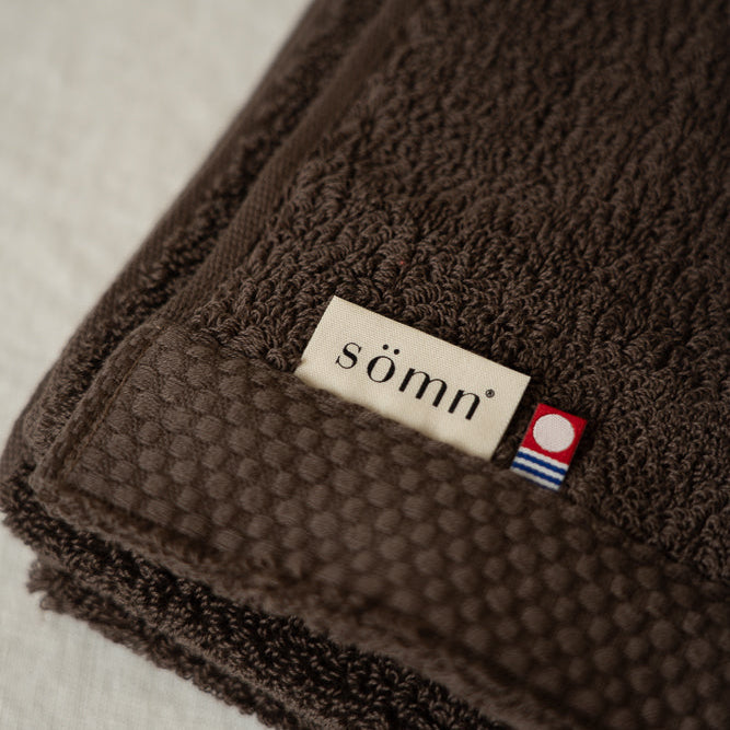 Brown textured towel with 'somn' brand label on a light background