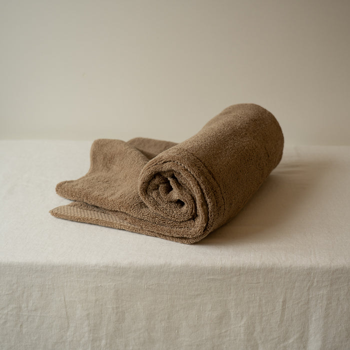 Rolled brown towel on a beige surface