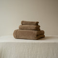 Stack of brown towels on a beige surface with a neutral background