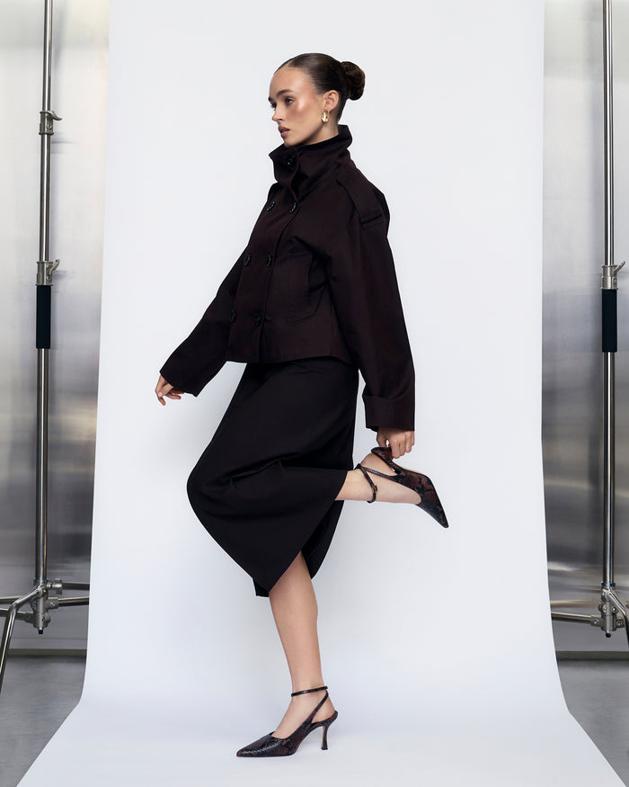 Woman wearing a black outfit and snake print heels against a white background