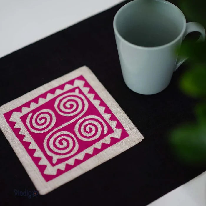 Närbild på rosa spiralformad tribalruta på svart linnetyg