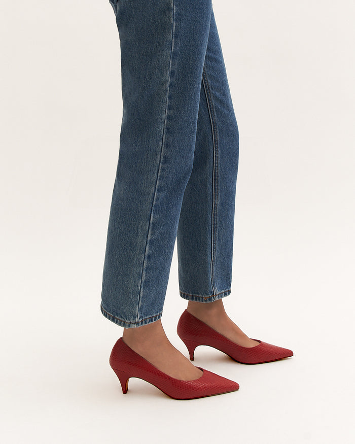 Red shoes worn with blue jeans on a white background