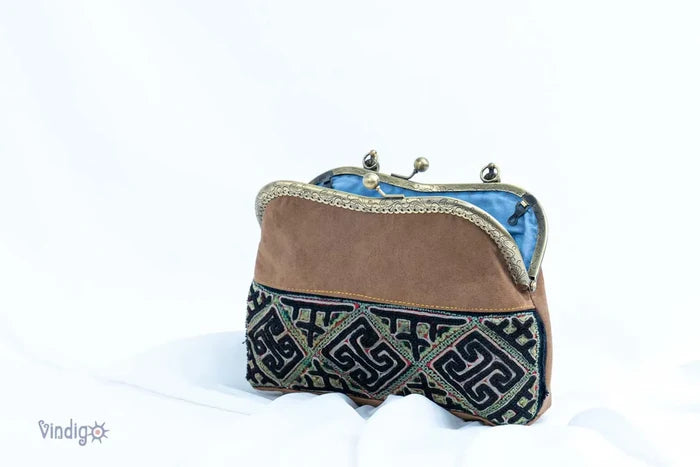 Side view of brown and black embroidered handbag standing upright