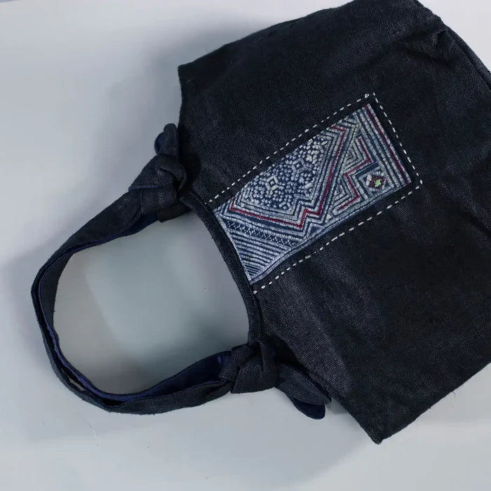 Angled view of black hemp bunny ear handbag with vintage H’Mong patch, sustainable handmade design