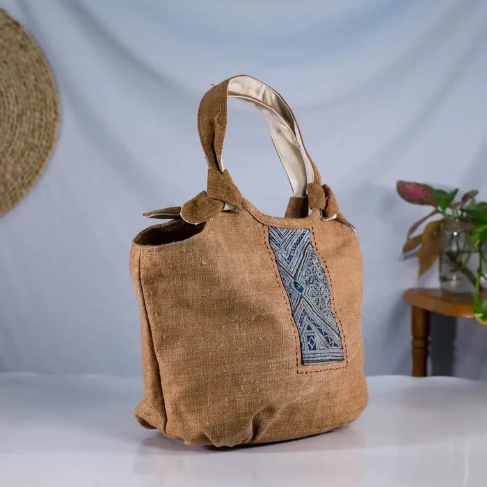 Angled view of brown hemp bunny ear handbag with vintage patch, sustainable handmade bag.