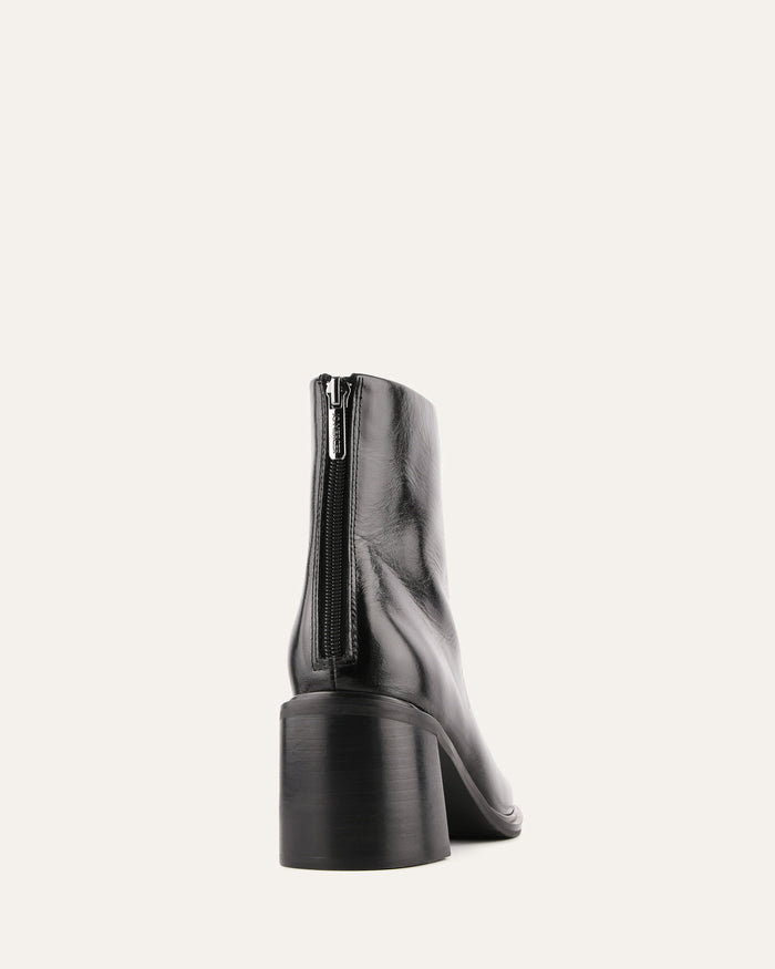 Black ankle boot with a zipper on a white background
