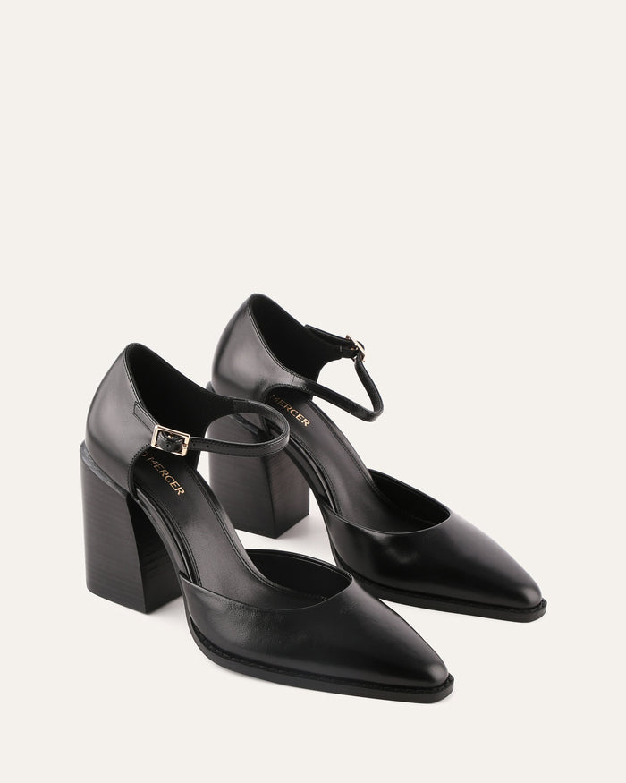 Black high-heeled shoes with ankle straps on a white background