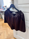 Core Edit Dark Chocolate Lounge Shorts hanging on a hanger, room setting.