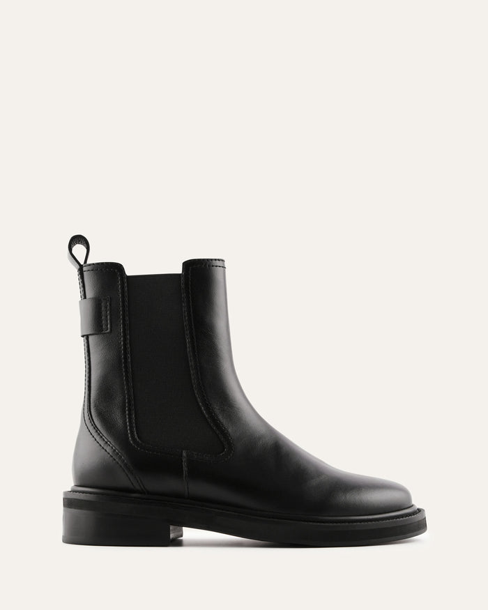 Black leather boot with a gold buckle on a white background