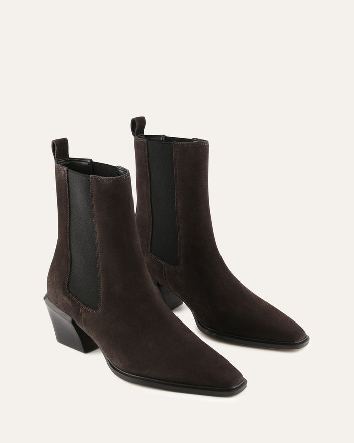 Pair of brown suede ankle boots on a light beige background