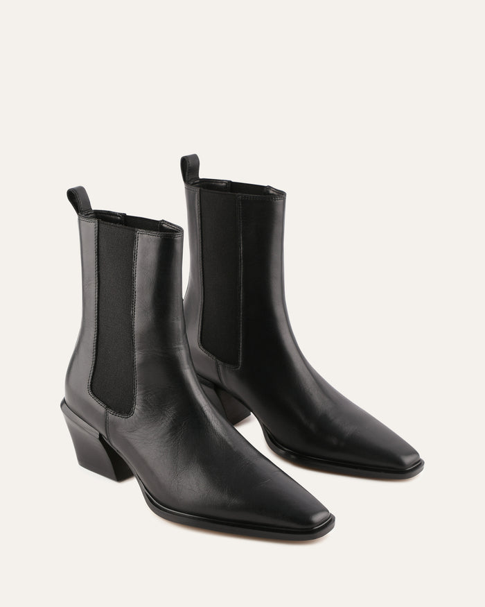 Pair of black leather Chelsea boots on a light gray background
