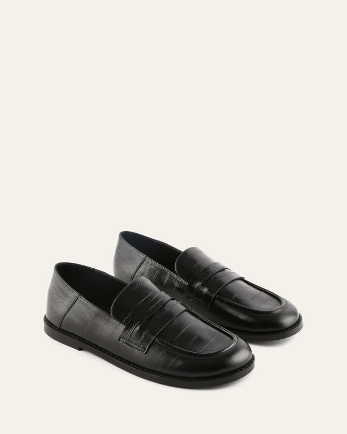Pair of black loafers on a light gray background