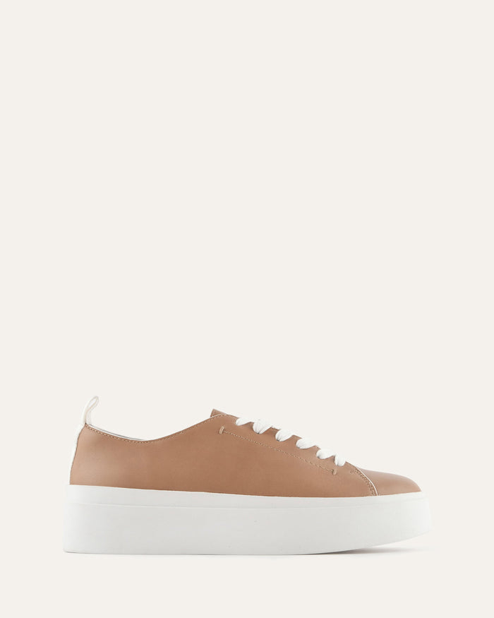 Brown sneaker with white sole on a light beige background