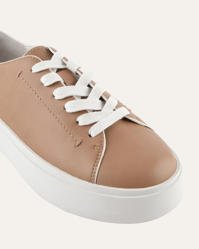 Brown sneaker with white laces on a light gray background