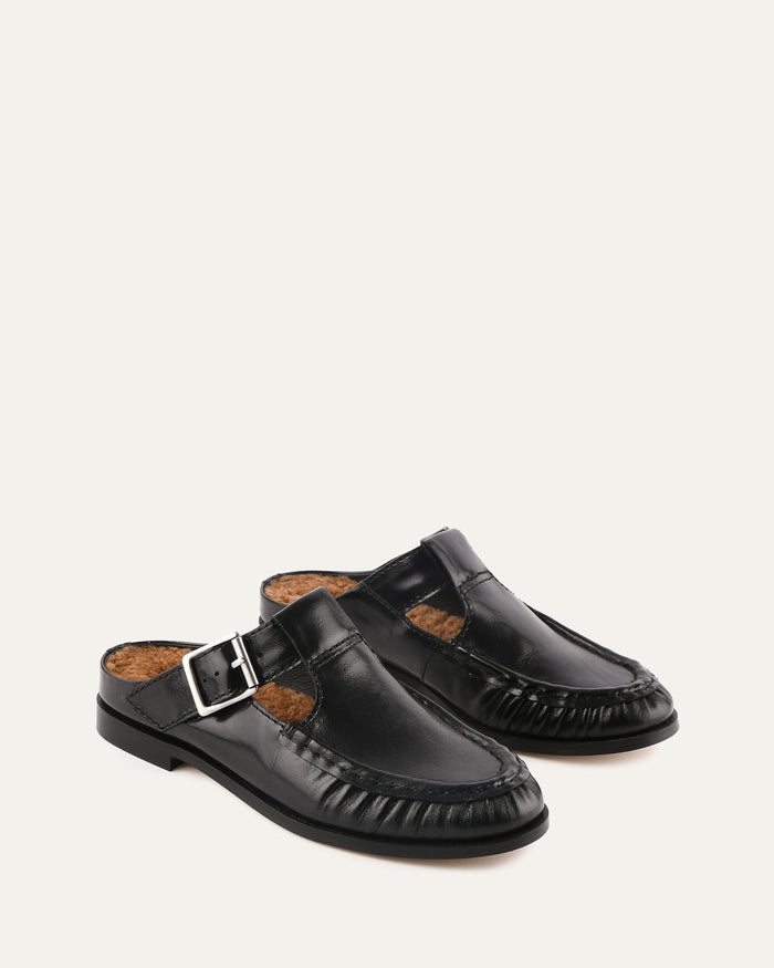 Pair of black leather clogs with a buckle on a white background