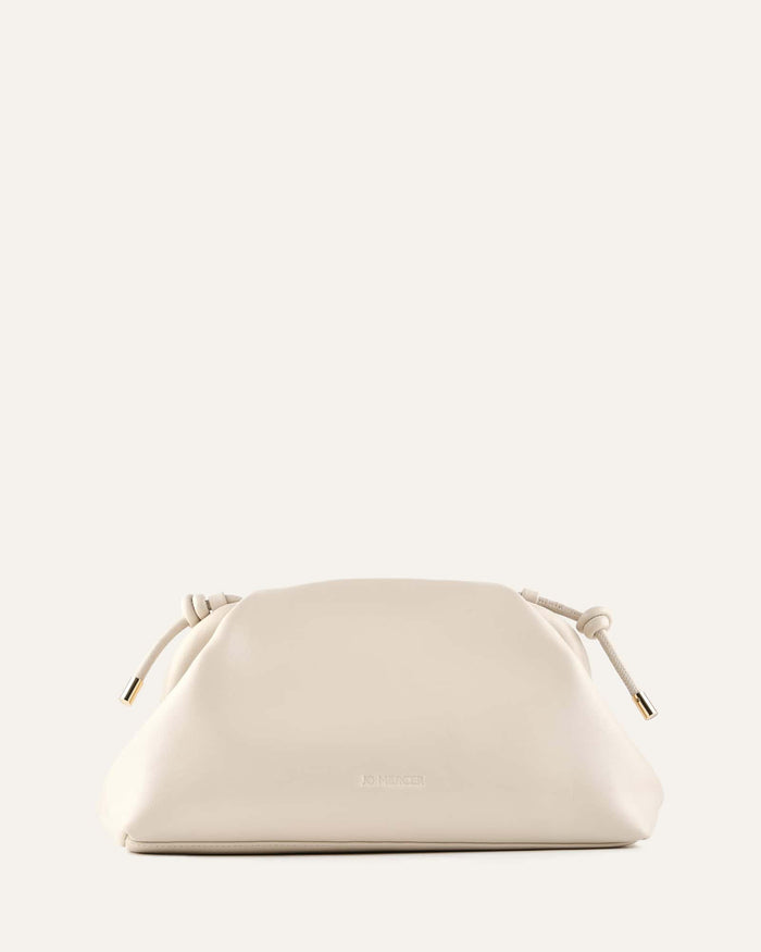 White handbag with gold accents on a light beige background