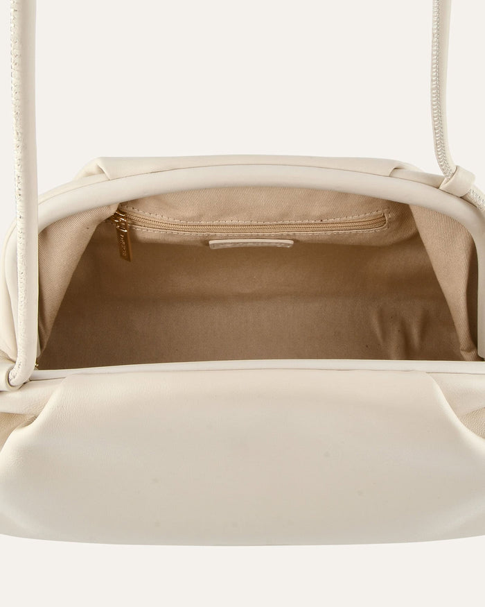 Close-up of a beige handbag with a gold zipper on a white background