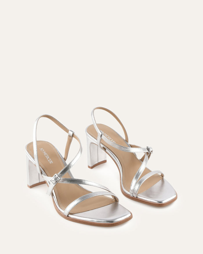 Silver high-heeled sandals on a light beige background