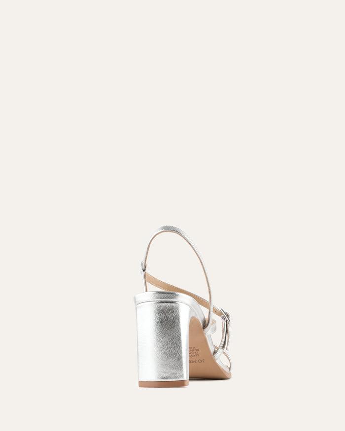 White sandal with a brown sole on a light beige background