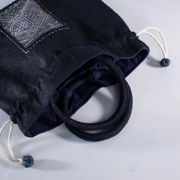 Open view of black hemp bucket bag showing cotton lining and vintage H’Mong patch