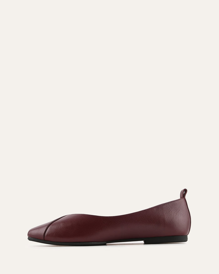 Maroon flat shoe on a light beige background