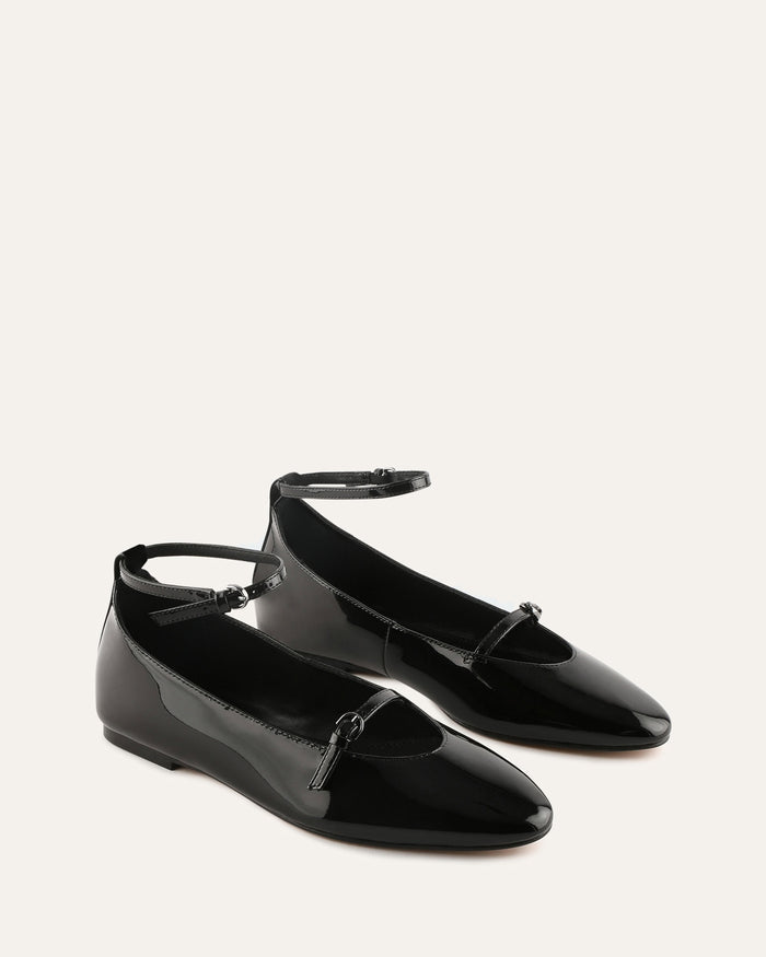 Black patent leather shoes on a light gray background