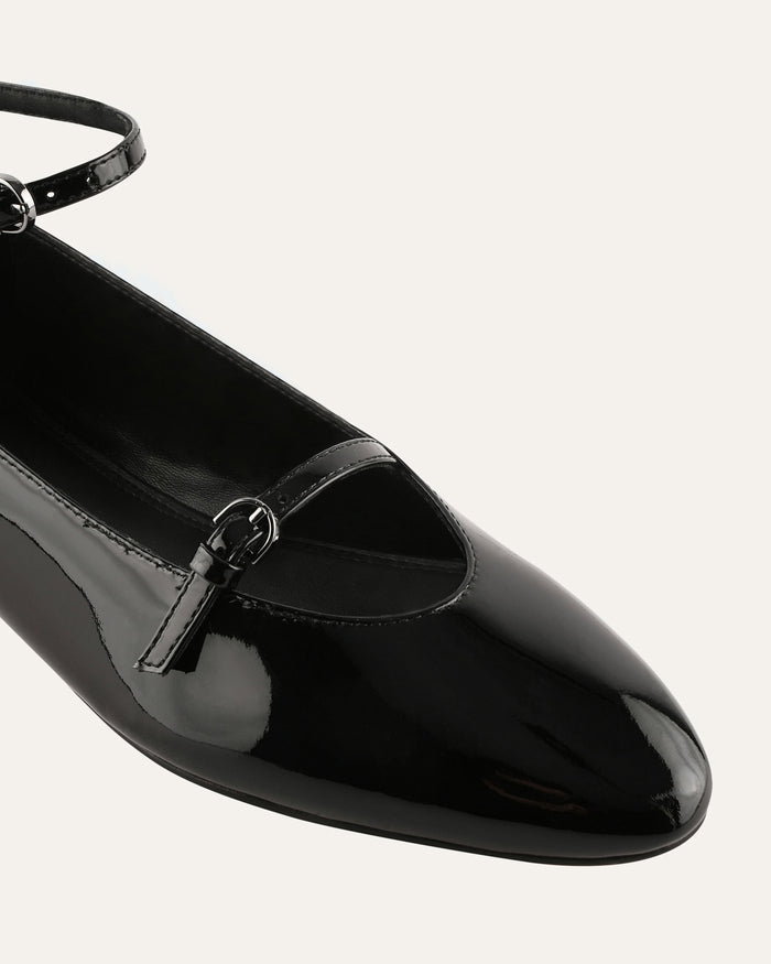 Black patent leather flat shoe with a slingback design on a white background