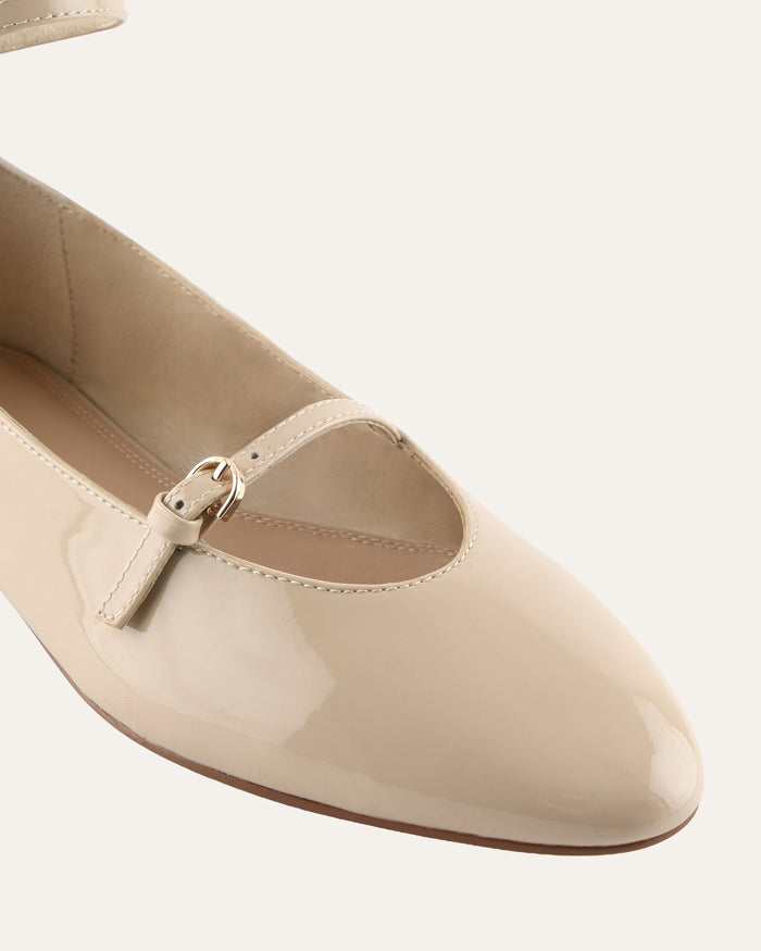 Beige flat shoe with a strap on a white background