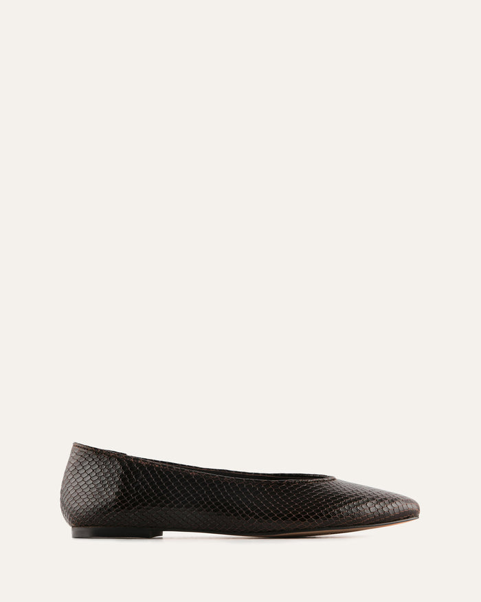 Black flat shoe on a light beige background