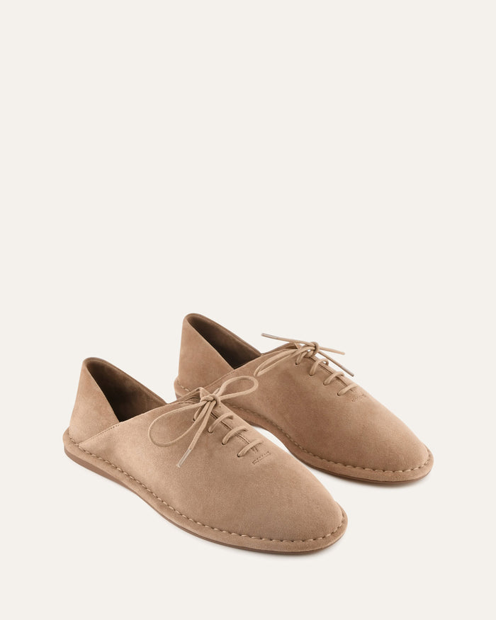 Pair of tan suede shoes on a white background