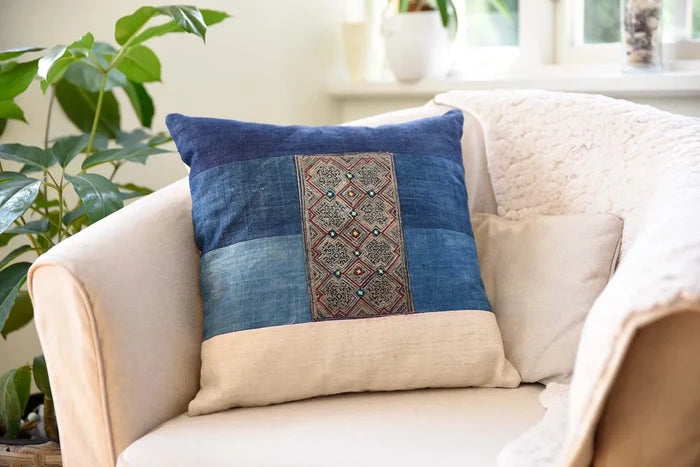 Handgjort blått kuddfodral med broderad mittpanel i soffmiljö