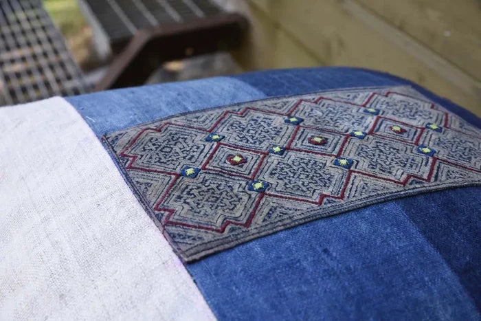 Texturdetalj av kuddfodral i blått tyg med handbroderad mittdel