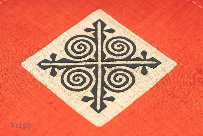 Detaljbild av svart geometriskt tribaltryck på orange kuddfodral