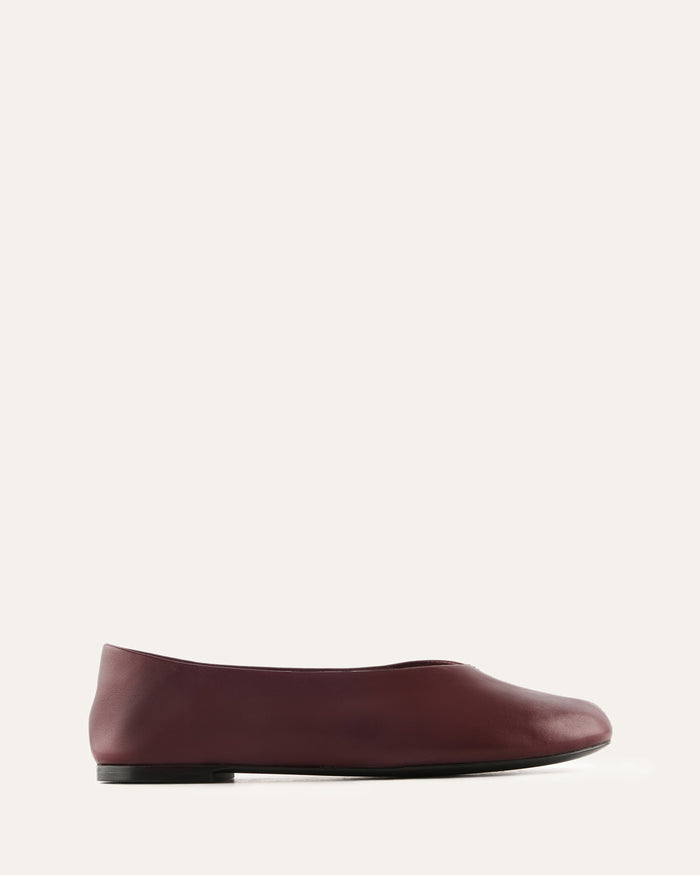 Maroon flat shoe on a light beige background