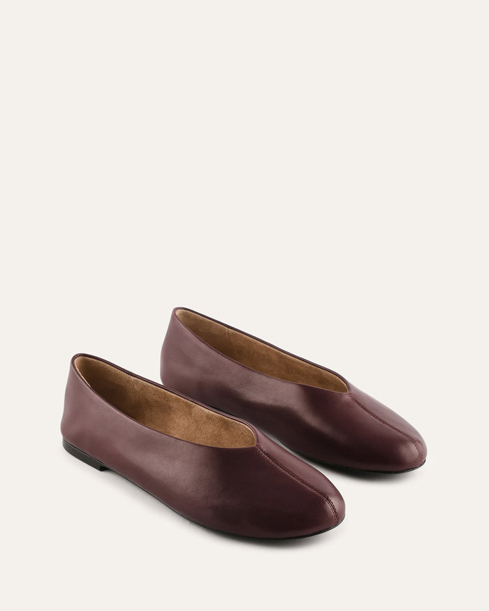 Pair of brown leather flats on a light beige background