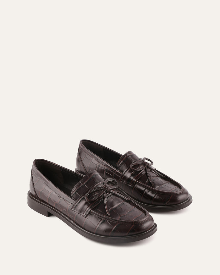 Pair of brown loafers on a light beige background