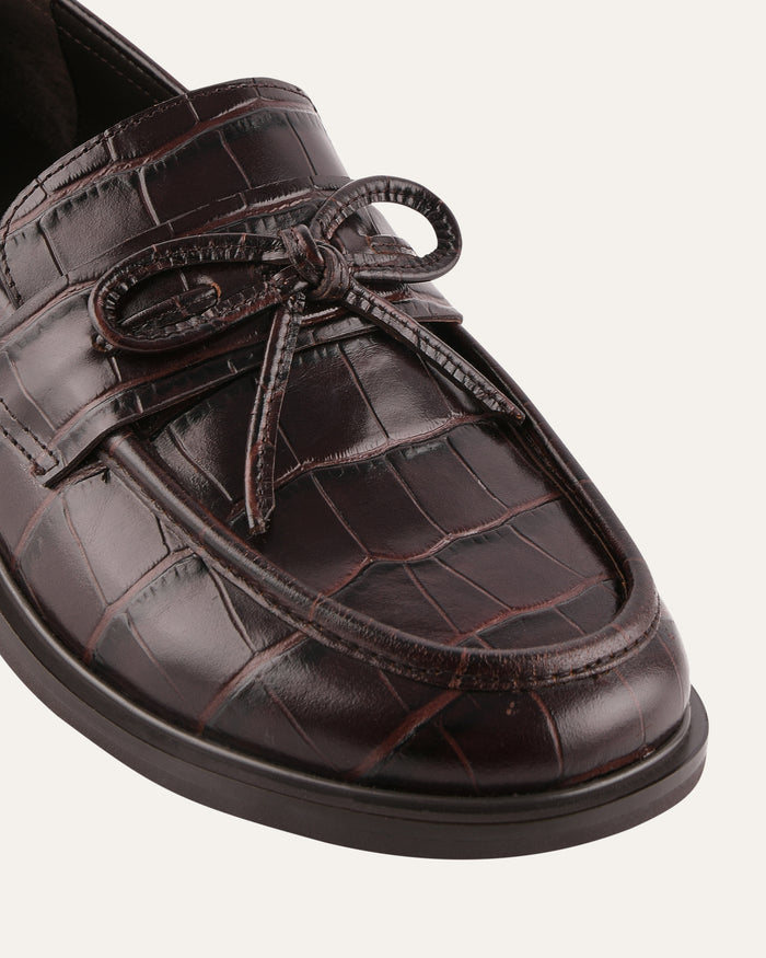 Brown leather shoe with a textured finish on a white background