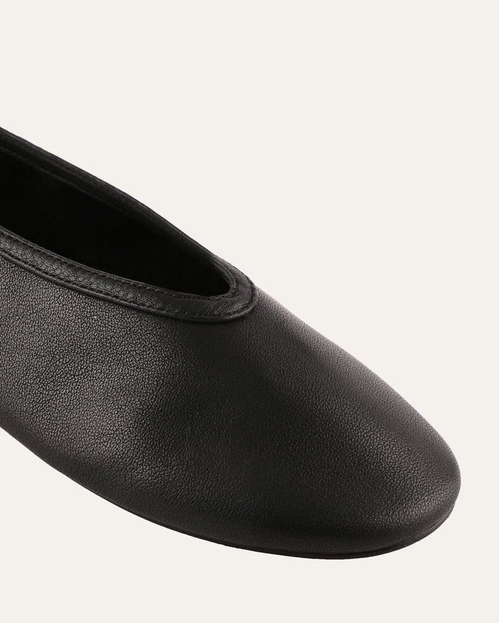 Black leather ballet flat shoe on a light gray background