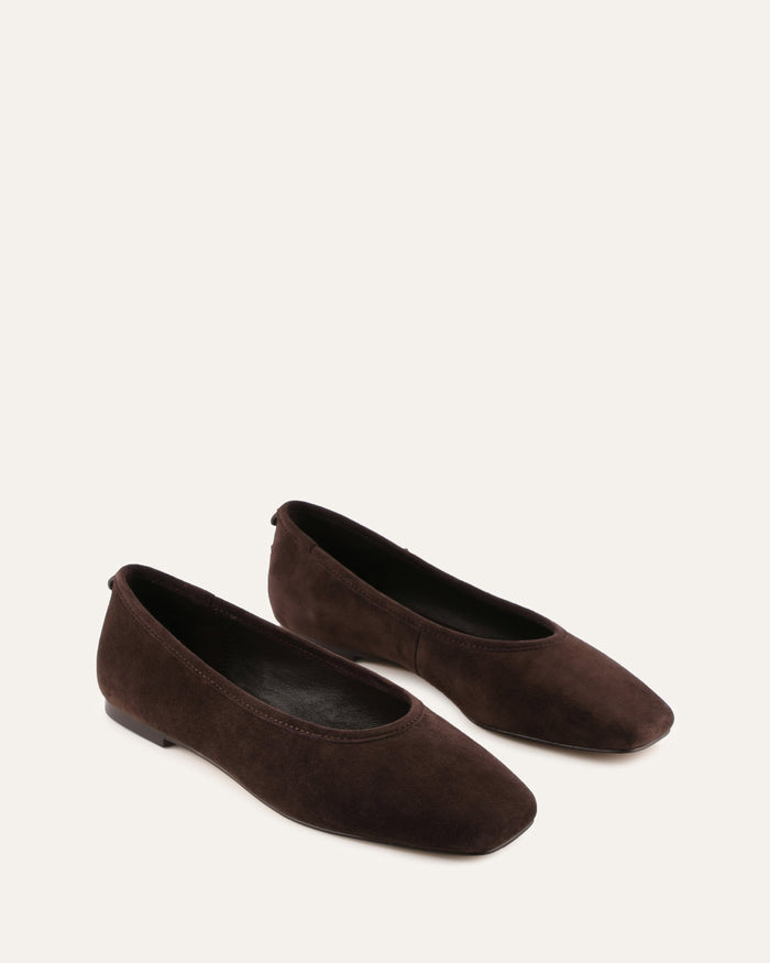 Pair of brown suede flats on a white background