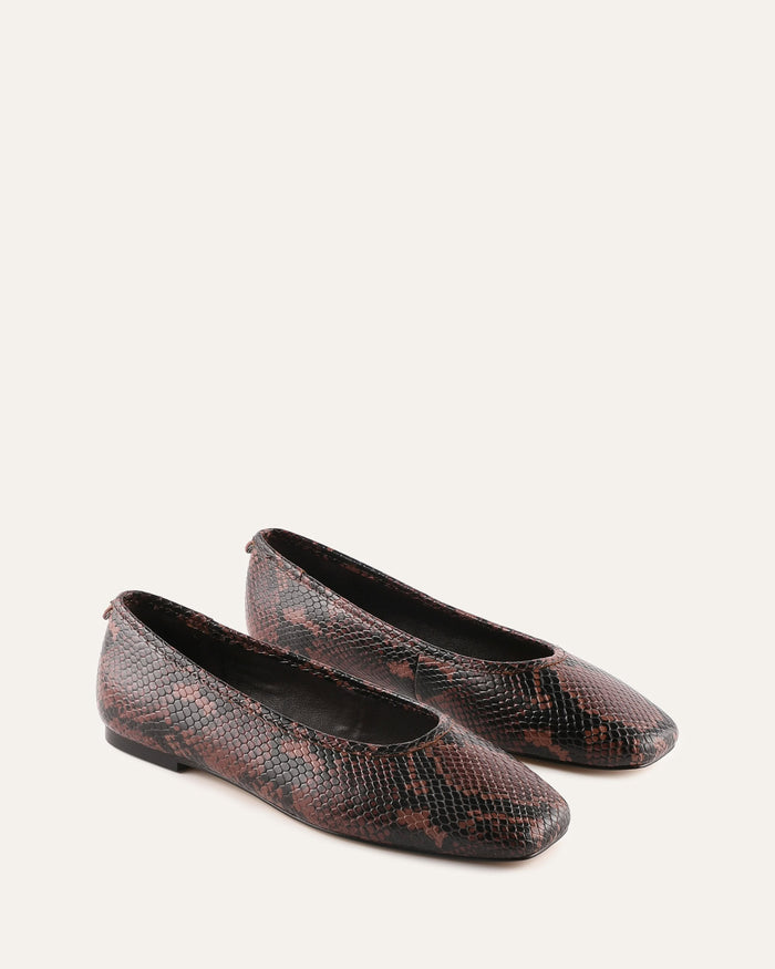 Pair of snakeskin-patterned flats on a white background