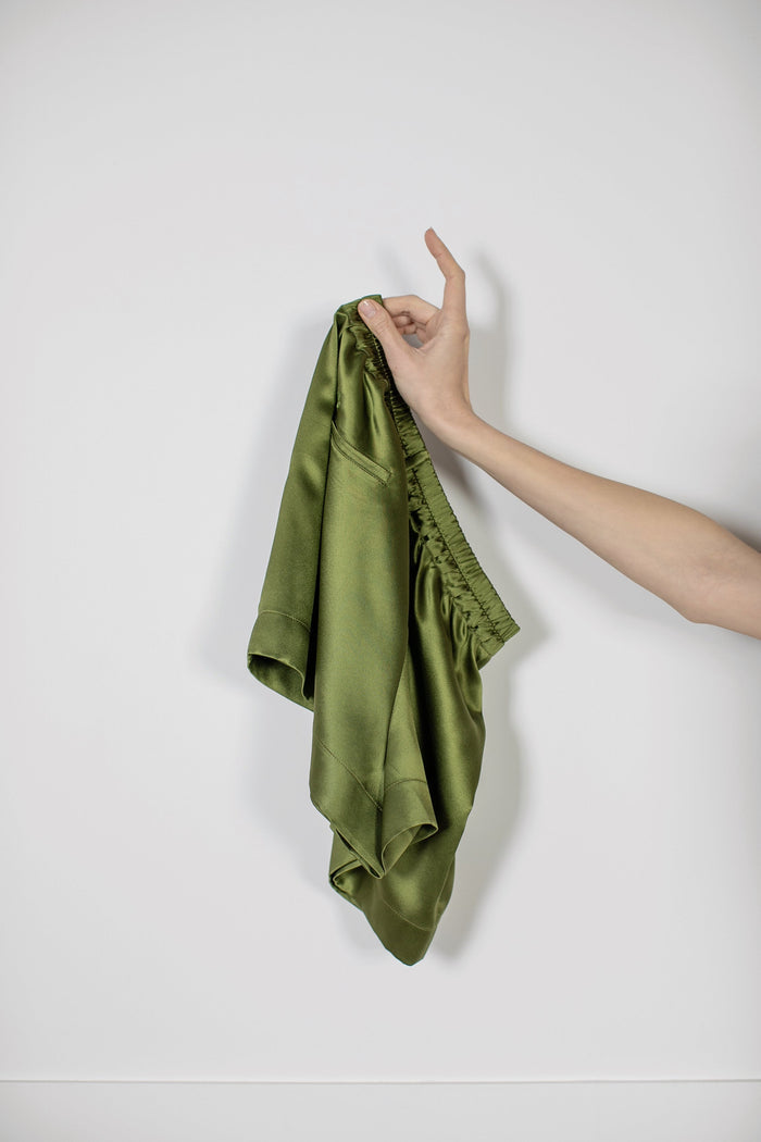 Signature Edit Green Lounge Shorts held loosely by the waistband.