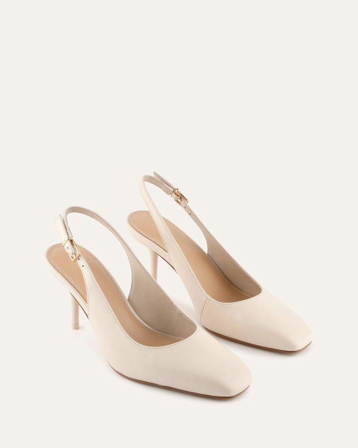 Pair of white high-heeled shoes on a light beige background