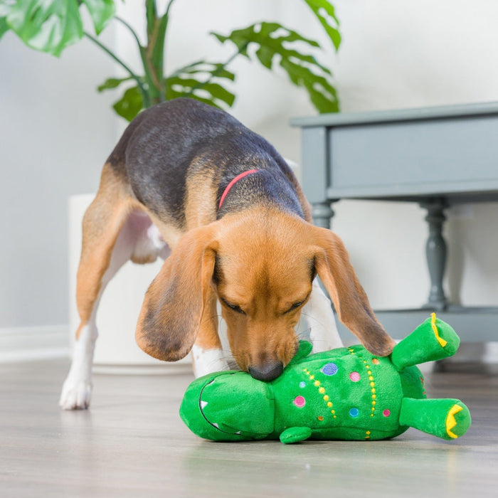 Dog playing with a green dinosaur plush toy featuring Tree Rex 2.0.